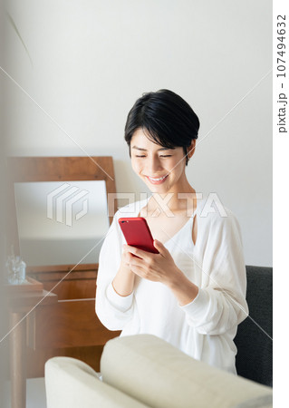 部屋でスマホを見る女性 107494632