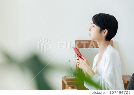 部屋でスマホを見る女性 部屋でスマホを見る女性 107494723