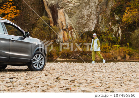happy woman at rocky beach near suv car road trip concept happy woman at rocky beach near suv car road trip concept 107495860