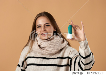 woman holds nasal spray for allergies on beige background 107497122
