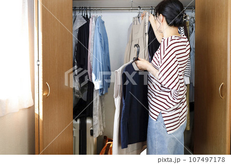クローゼットの前で服を手に取る女性 107497178
