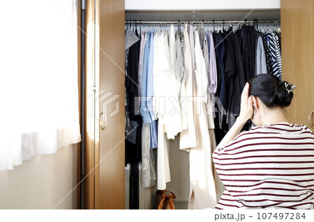 クローゼットの前で悩む女性 107497284