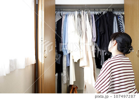 クローゼットの前で悩む女性 107497287