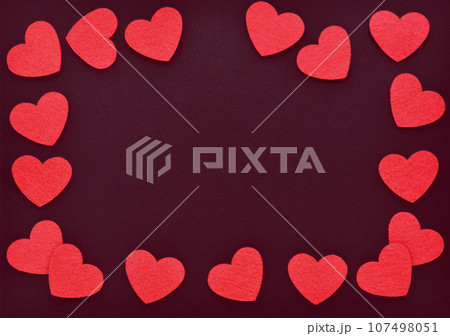 Background for your greetings for a Valentine's day. Frame with red felt hearts on dark red paper 107498051