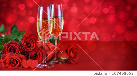 Romantic date night concept. Champagne, hearts, gift and roses on a festive red background. Romantic date night concept. Champagne, hearts, gift and roses on a festive red background. 107498055