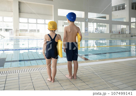 室内プールでビート板を持つ兄弟の後ろ姿 107499141