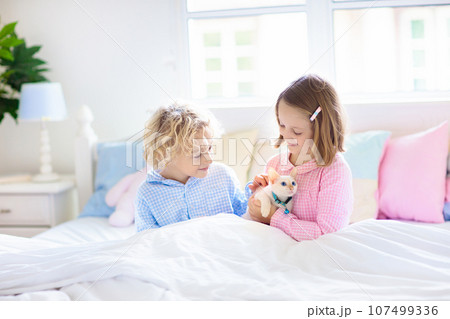 Kids play with baby cat. Child and kitten in bed. Kids play with baby cat. Child and kitten in bed. 107499336