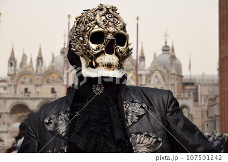 Person dressed up for Carnival of Venice wearing skull mask and black suit 107501242