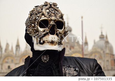 Person dressed up for Carnival of Venice wearing skull mask and black suit 107501335