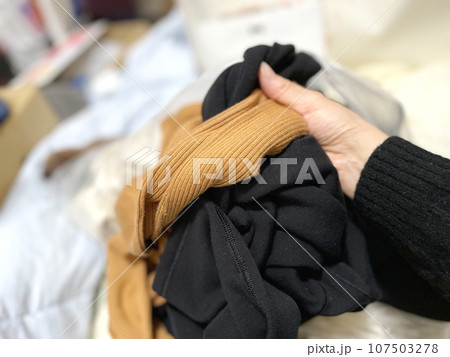 散らかった洋服を持つ手 107503278