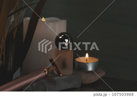 High frequency rejuvenating facial massager T-Vibe and serum bottle. Face and neck lifting massagers and a glass bottle of oil, essential water for body care on stone podium Dark key beauty photo. 107503908