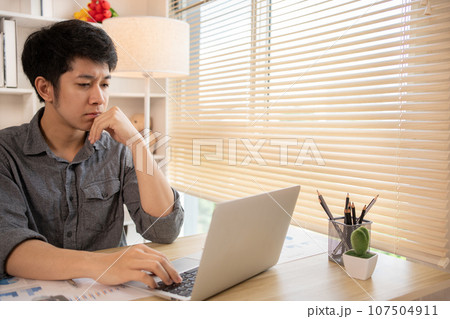 Stressed Young Businessman Facing Financial Loss in Corporate Office, Depressed man Dealing with Financial Setback, Stress and Money Problems, Anxiety and Worry Concept. Stressed Young Businessman Facing Financial Loss in Corporate Office, Depressed man Dealing with Financial Setback, Stress and Money Problems, Anxiety and Worry Concept. 107504911