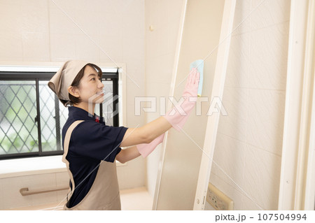 浴室の扉の清掃をするハウスクリーニングの女性作業員 浴室の扉の清掃をするハウスクリーニングの女性作業員 107504994