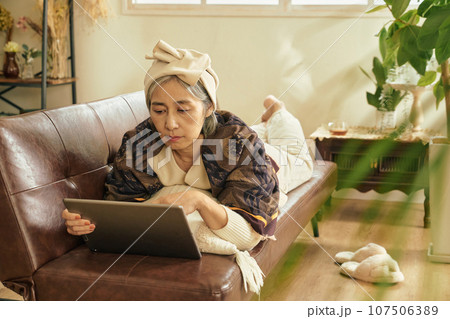 部屋でタブレットを触るシニア女性 部屋でタブレットを触るシニア女性 107506389