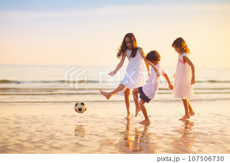 Kids play football on tropical beach at sunset Kids play football on tropical beach at sunset 107506730