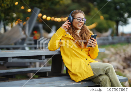 Young woman listens to music, audiobook. Communication in social networks. Lifestyle concept. 107507867