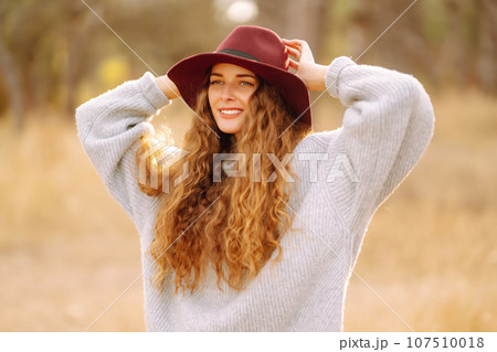 Stylish woman in sweater and hat enjoys autumn nature. People, freedom, lifestyle, travel concept. Stylish woman in sweater and hat enjoys autumn nature. People, freedom, lifestyle, travel concept. 107510018