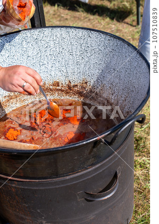 stew cooking in a cauldron, cooking goulash in a cauldron. 107510839