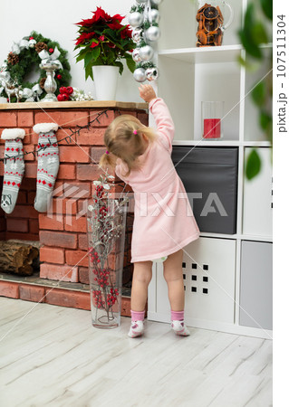 Young child looking at Christmas ornaments in decorated room Young child looking at Christmas ornaments in decorated room 107511304