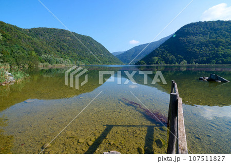 Nature background with a lake of Segrino in North of Italy, in Lombardy and Italian Alps mountains. Clean clear blue sky. 107511827