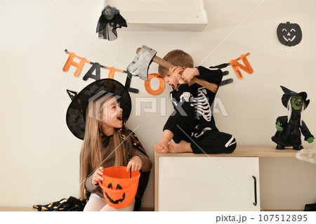 Children in skeleton and witch costume laughing at home 107512895