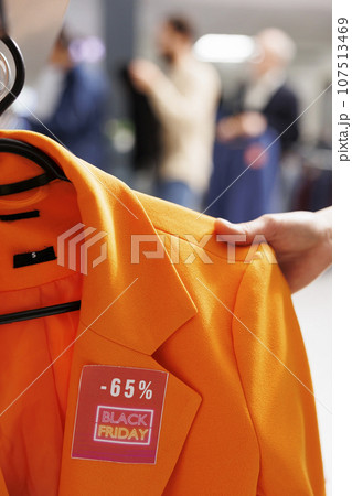 Sale discount tag on clothing item in fashion boutique, people buying clothes at discounted prices during Black Friday sales. Shopper customer looking for bargains in outlet store, checking price Sale discount tag on clothing item in fashion boutique, people buying clothes at discounted prices during Black Friday sales. Shopper customer looking for bargains in outlet store, checking price 107513469
