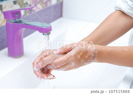 woman washes her hands under running water from a tap in the bathroom, concept of hygiene and protection from bacteria woman washes her hands under running water from a tap in the bathroom, concept of hygiene and protection from bacteria 107515808
