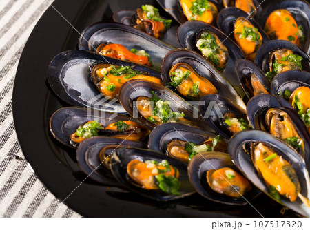 Closeup of steamed mussels on black dish 107517320