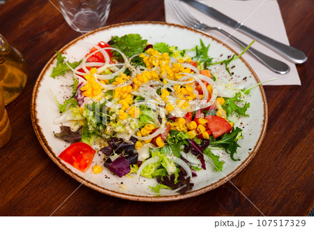 Appetizing salad with corn, arugula and tomatoes on plate 107517329