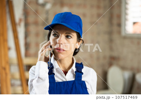 Female builder talking on phone with owner of building under renovation 107517469