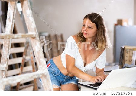 Young woman designer using laptop during repair works Young woman designer using laptop during repair works 107517555