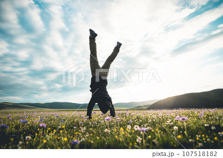 Woman hiker doing a handstand on high altitude mountain meadow 107518182