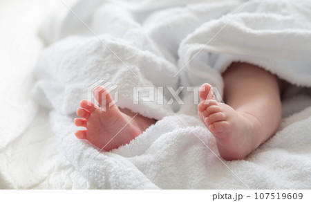 Delicate feet of a newborn under a towel's embrace. Concept of innocence and warmth Delicate feet of a newborn under a towel's embrace. Concept of innocence and warmth 107519609