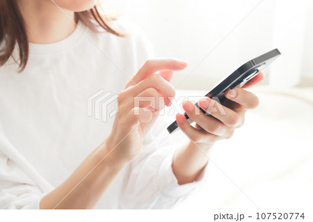 スマホを使う女性の手元 107520774