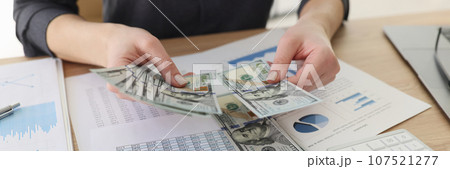 Woman counts money over table with papers and handcuffs 107521277