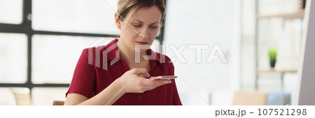 Woman with paper dials number on mobile phone in office Woman with paper dials number on mobile phone in office 107521298