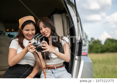 Two happy Asian female are checking the pictures on the camera, having fun during their road trip 107522375