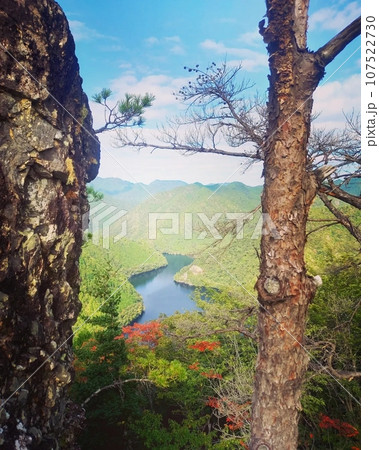 紅葉の始まった木々と湖 107522730