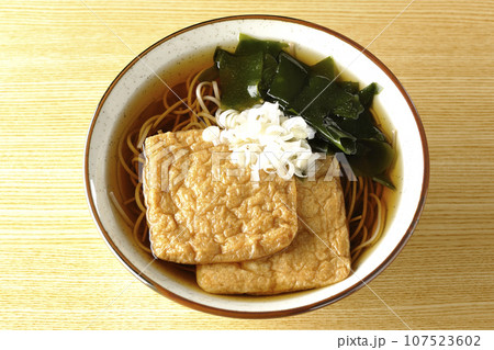 油揚げ2枚とワカメと葱が乗ったきつね蕎麦を俯瞰で撮影 油揚げ2枚とワカメと葱が乗ったきつね蕎麦を俯瞰で撮影 107523602