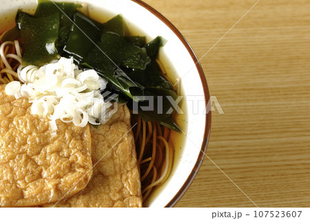 油揚げ2枚とワカメと葱が乗ったきつね蕎麦を俯瞰で撮影 油揚げ2枚とワカメと葱が乗ったきつね蕎麦を俯瞰で撮影 107523607