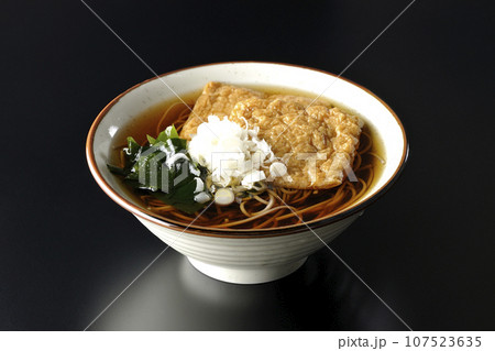 油揚げ2枚とワカメと葱が乗ったきつね蕎麦を黒背景で撮影 油揚げ2枚とワカメと葱が乗ったきつね蕎麦を黒背景で撮影 107523635