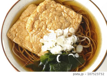 油揚げ2枚とワカメと葱が乗ったきつね蕎麦を白背景で俯瞰撮影 油揚げ2枚とワカメと葱が乗ったきつね蕎麦を白背景で俯瞰撮影 107523732