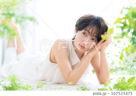 リビングで寝転んでスキンケアをするミドルの女性 リビングで寝転んでスキンケアをするミドルの女性 107525875