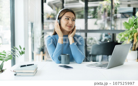 Happy Asian girl wearing headphones listening to music enjoying on smartphone digital. relaxation concepts 107525997