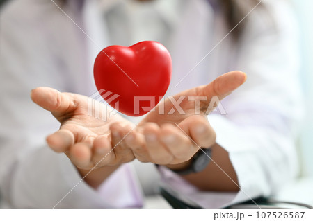 Red heart floating over opened hands. Health care, cardiological, medical and charity concept 107526587
