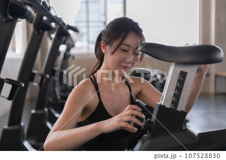 Asian woman preparing exercise equipment in the gym. Asian woman preparing exercise equipment in the gym. 107528830