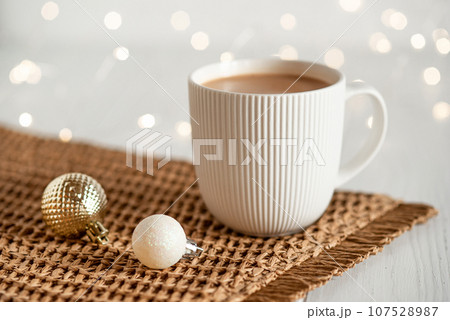 A white cup with hot coffee or tea on a white wooden table. 107528987
