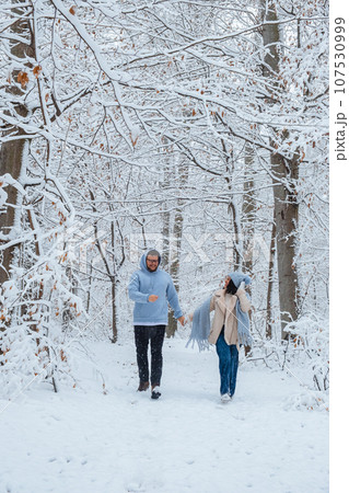 Couple in love running through a winter forest on a snowy day 107530999