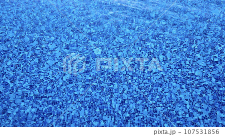The bottom of a swimming pool made of multi-colored tiles under a layer of water 107531856