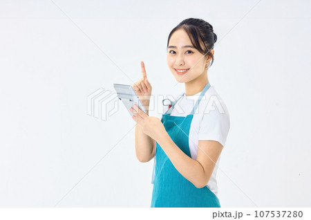 電卓を使うエプロン姿の若い主婦 電卓を使うエプロン姿の若い主婦 107537280